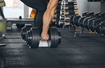 Fototapeta na wymiar Bodybuilder workout. Athlete picked up heavy dumbbells. Close-up photo of Heavy dumbbells weighing 50 kilograms. Sports equipment and dumbbells. Interior of the gym. Camera focus on the hands