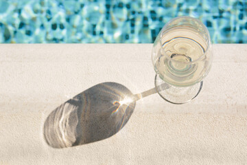 Glass of tasty wine on swimming pool edge, above view. Space for text