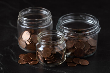 Glass jars with coins on black marble table