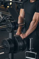 Fototapeta na wymiar Muscular strong arms of bodybuilder. Barbells plates. Muscular man trains strong arms. Camera focus on the hands. Barbell workout