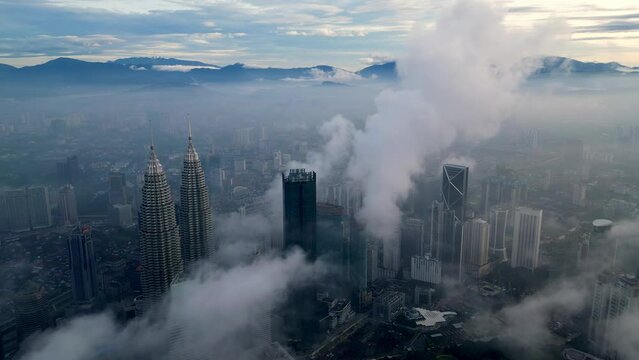 Drone shot over KLCC twin tower and surrounding skyscraper in foggy cloud
