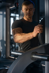 Fototapeta na wymiar Workout in the gym. Strong and muscular arms of a man. The concept of a healthy body, a strong man. A sunbeam shines on the muscles of the arm in the foreground. Template for watches and accessories
