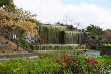 waterfall in the park of The Port  on the tropical island of La Réunion France in the landscaped garden with flowers 