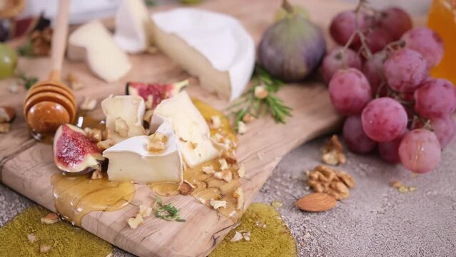 Sliced pieces of Camembert or brie cheese on wooden cutting board at domestic kitchen