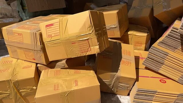 Tossing brown box package to pile of parcel boxes slow motion on a sunny day