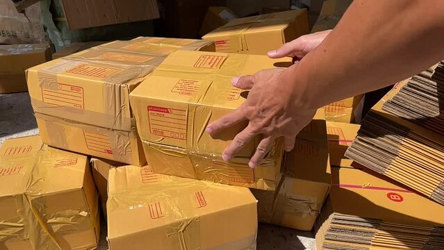 Tossing brown box package to pile of parcel boxes slow motion on a sunny day
