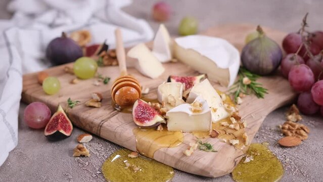 Sliced pieces of Camembert or brie cheese on wooden cutting board at domestic kitchen