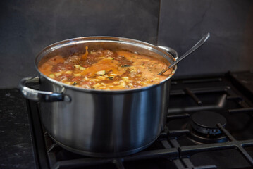 Gotująca się zupa toskańska na czarnej kuchence gazowej - obrazy, fototapety, plakaty