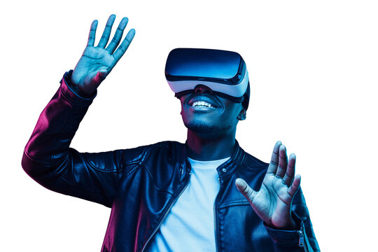 Young african man wearing virtual reality goggles with hands up, playing game in metaverse