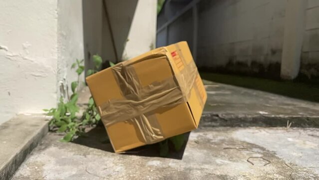 Brown box package falling on ground slow motion on a sunny day