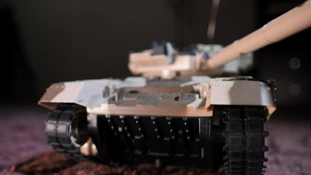 Close-up shot of an isolated radio-controlled toy tank that drives, rotates the turret and fires from the muzzle. Military children's toys. A game of war games with heavy weapons. RC toy tank