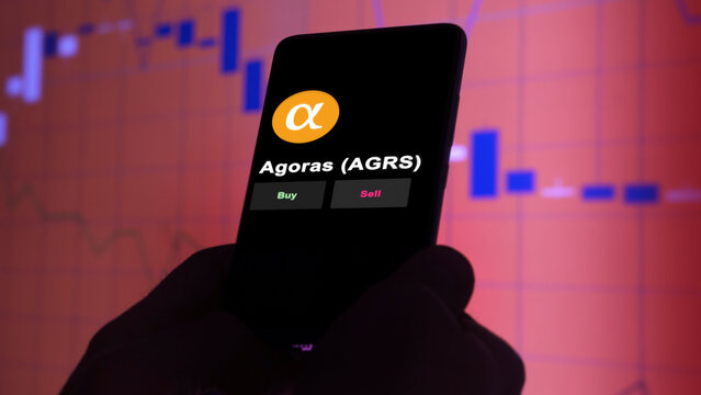 10th December 2022, Berlin. An investor's analyzing the Agoras- Currency of Tau token 'AGRS' coin on screen. A phone shows the crypto's prices to invest

