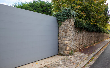 Aluminum Sliding Modern Gray Portal Design Suburban Slide House Garden Door. Stone Fence with Metal Gates for Access to a House in Paris, France.