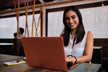 Smiley businesswoman working with a laptop in a cafeteria - Powered by Adobe