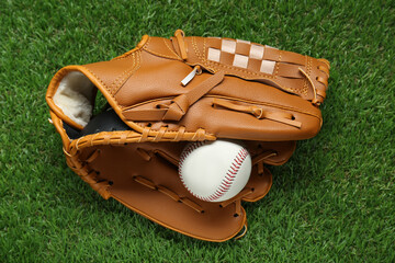 Catcher's mitt and baseball ball on green grass, top view. Sports game