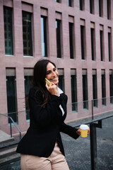 Businesswoman talking to the mobile and drink a coffee outdoors