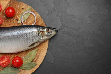 Tray with salted herring, onion, bay leaves and cherry tomatoes on black table, top view. Space for text