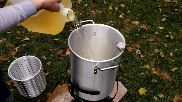 Pouring peanut and soy oil blend into large pot preparing it for deep frying turkey