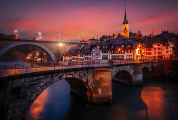 Incredible vivid cityscape. Scenic view Historical Old Town of Bern city with colorful sky, view on bridges over Aare river and church tower during dramatic sunset. Bern. Switzerland. Europe