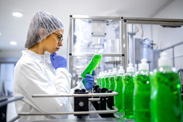 Female technologist controlling production of cleaning supplies or sanitation chemicals for cleaning industry. Checking quality of detergent.
