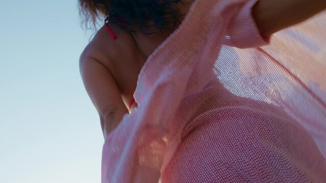 A female in a red two-piece swimsuit is preparing to swim or sunbathe.
Woman takes off her beach dress and prepares for sunbathing on the beach.