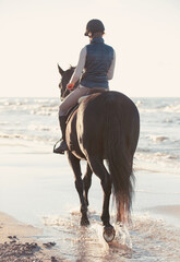 Young Lady riding horse on coastline in rays of sunlight