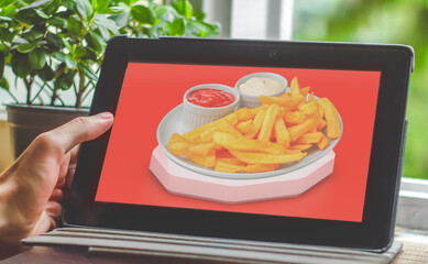 hand holding a tablet with plate of fast food on ther screen