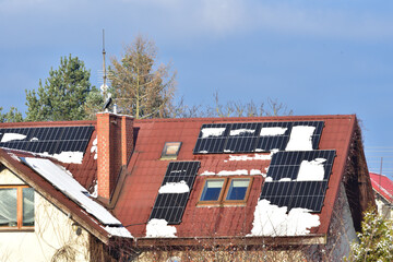 Panele fotowoltaiczne na dachu pokryte częściowo śniegiem - obrazy, fototapety, plakaty