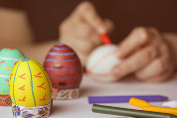 Fototapeta na wymiar A person is painting Easter eggs with colored crayons. Preparing for Easter religious festivities 2023. Hobby, leisure, spring break at home. Family holiday. Preparing decorations. Festive food.