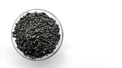 Black moong, mung or whole black urad beans in a glass bowl isolated on white background. Copy space