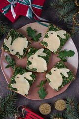 Sandwiches for the New Year 2023 from canned tuna, eggs and greens, decorated with rabbit from cheese on brown table, Top view