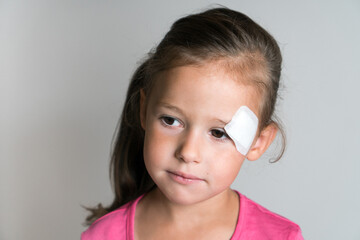 Close up sad, nice, lovely, adorable dark haired little child, girl with white patch bandage on...
