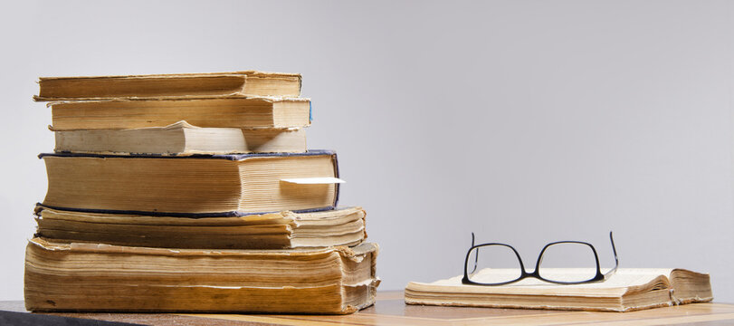  stack of old books and reading glasses lie on the table. selective focus .High quality photo