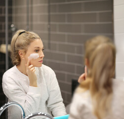 Woman looking in the mirror Applying the cream..Magic anti-aging cream