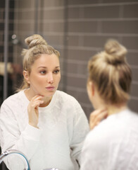 Obraz premium Woman looking in the mirror Applying the cream..Magic anti-aging cream