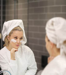 Woman looking in the mirror Applying the cream..Magic anti-aging cream