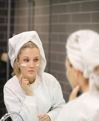 Woman looking in the mirror Applying the cream..Magic anti-aging cream