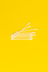 White cotton swabs on a bright yellow background
