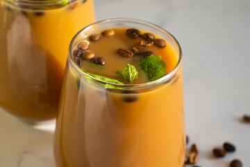 Cold coffee with milk and mint on a light background