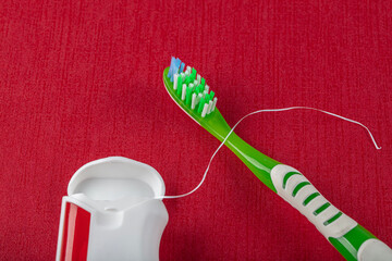 Dental floss and toothbrushes on red background. Care of teeth health. Everyday routine teeth...