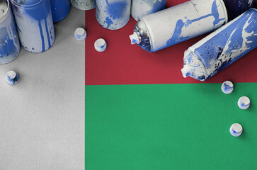 Madagascar flag and few used aerosol spray cans for graffiti painting. Street art culture concept,...