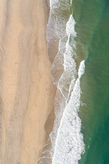 overhead drone aerial view of the waves on a beach shore