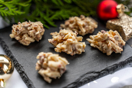 Mandelsplitter mit wei&szlig;er Schokolade auf einer Schieferplatte mit Weihnachtsdekoration
