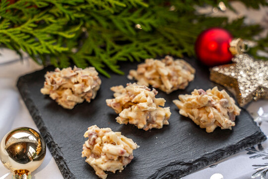 Mandelsplitter mit wei&szlig;er Schokolade auf einer Schieferplatte mit Weihnachtsdekoration