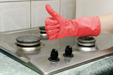 Cleaning dirty gas stove from grease, food leftovers deposits. woman's hand in protective glove...