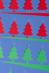 blue stencils with stylized paper holiday tree cutouts on red and green