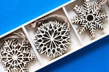 box with wooden snowflake ornaments on blue paper
