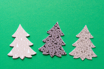 three sets of stylized paper holiday trees on green