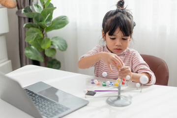 Asian Little girl studies the solar system in geography class. looking at the scale model of planets