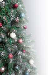 Christmas tree with branches sprinkled with hoarfrost and elegantly decorated with Christmas balls, beads, garlands